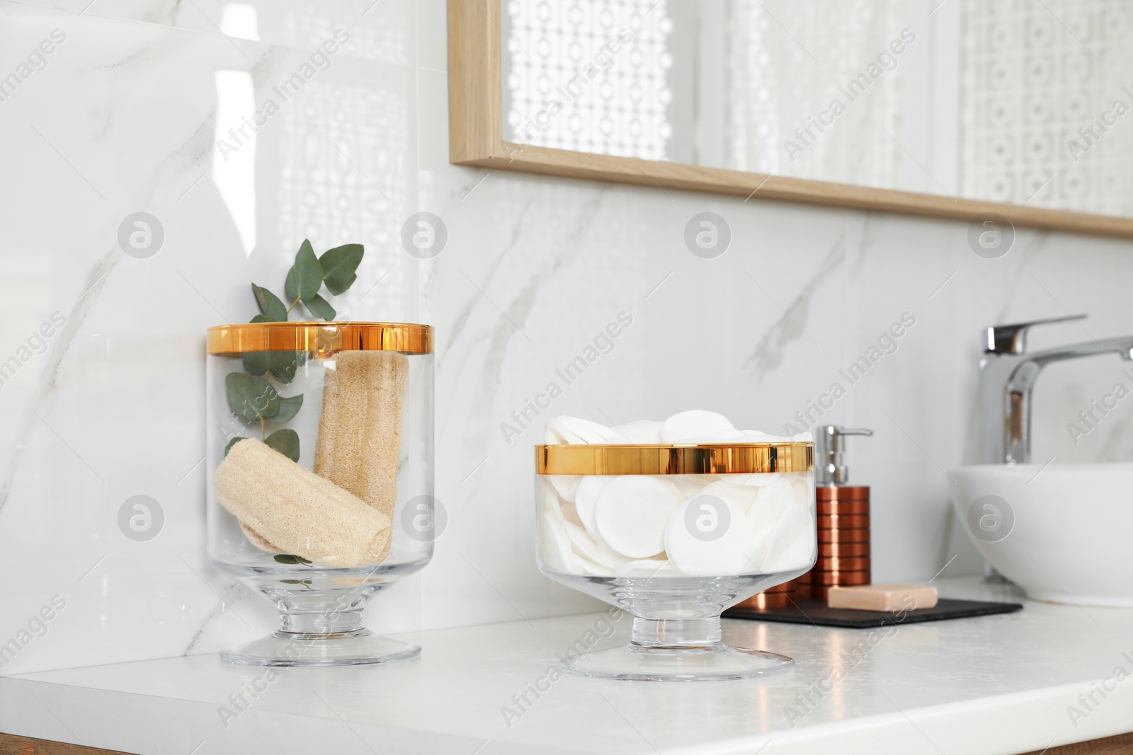 Photo of Jars with cotton pads and loofah sponges on bathroom countertop