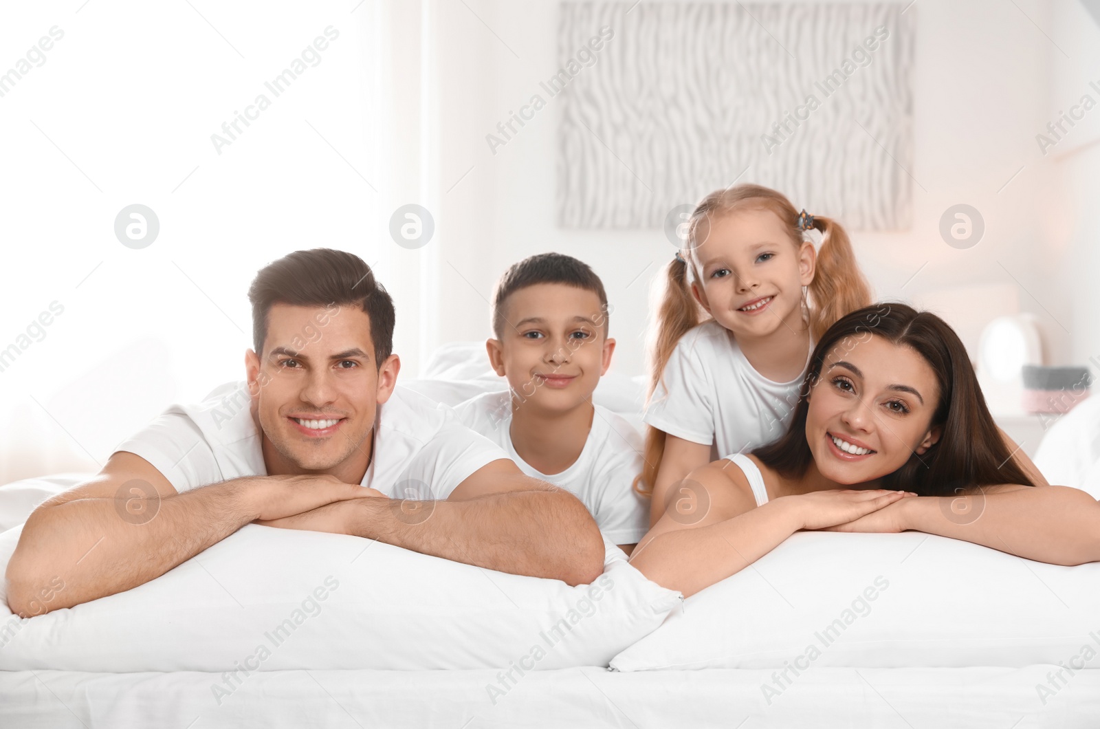 Photo of Portrait of happy family on large bed in room