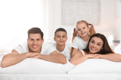 Photo of Portrait of happy family on large bed in room