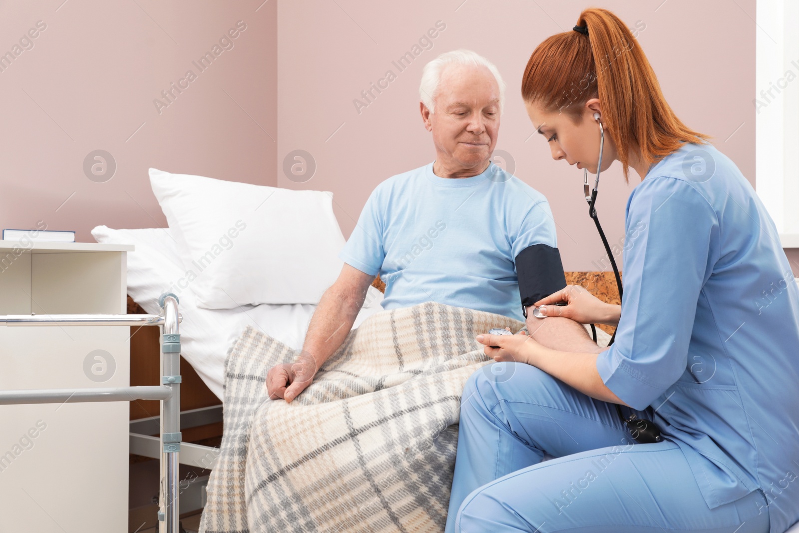 Photo of Nurse measuring senior man's blood pressure in hospital ward. Medical assisting