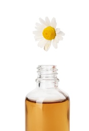 Essential oil dripping from chamomile petal into glass bottle on white background