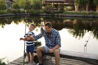 Dad and son fishing together on sunny day