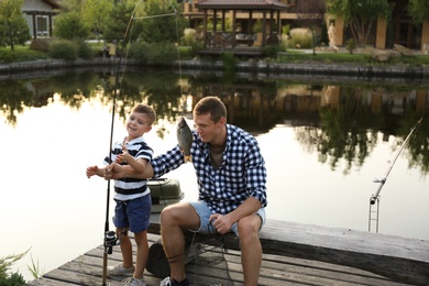 Photo of Dad and son fishing together on sunny day