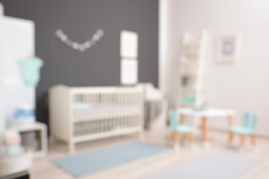 Blurred view of cute baby room interior with modern crib near dark wall