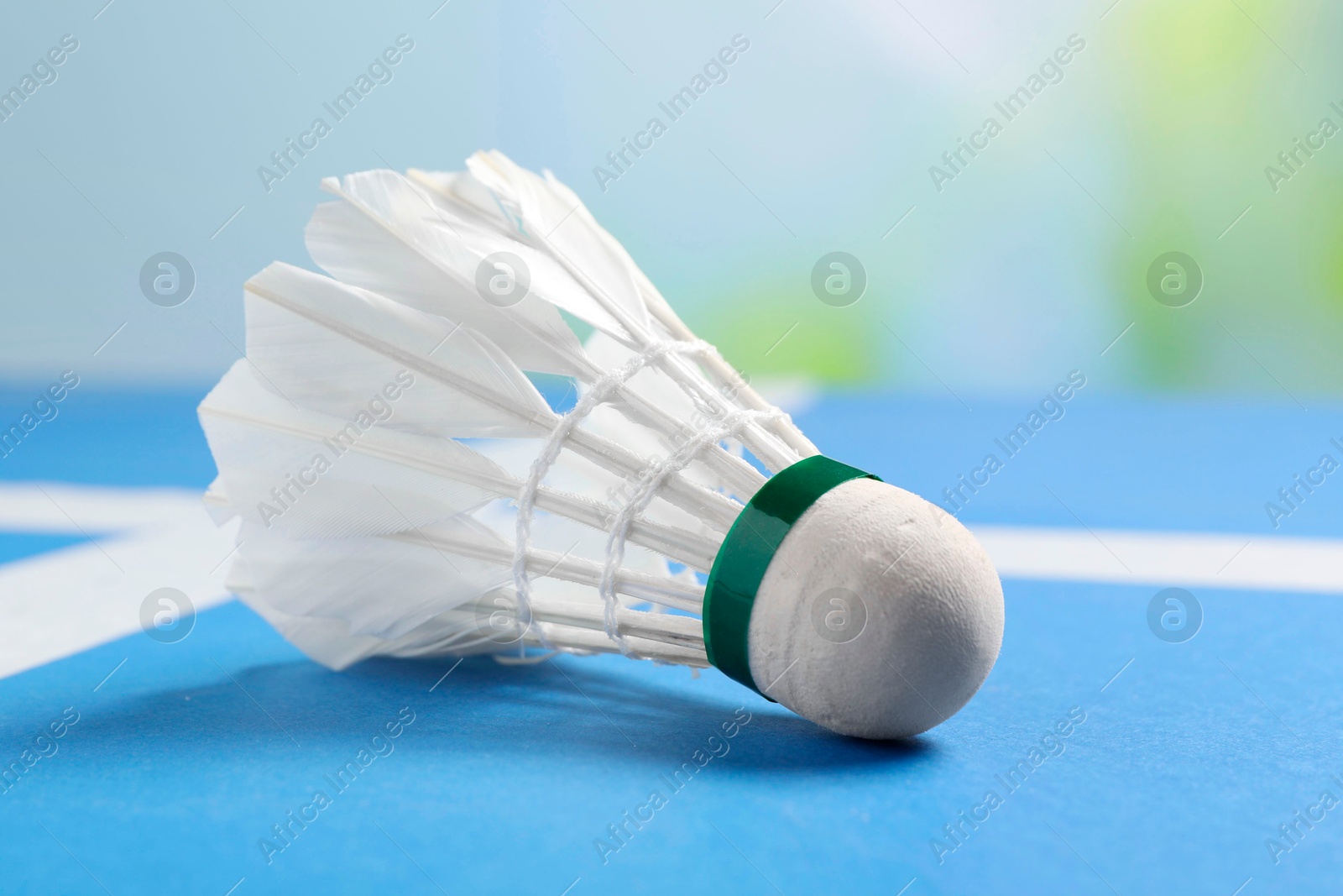 Photo of Feather badminton shuttlecock on blue table against blurred background, closeup