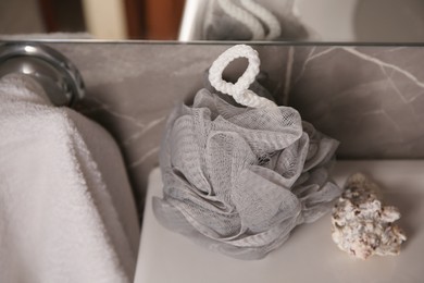 Photo of Grey shower puff and seashell on sink in bathroom, closeup