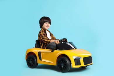 Photo of Little child driving yellow toy car on light blue background