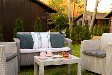 Photo of Outdoor breakfast with tea and croissants on rattan table in garden