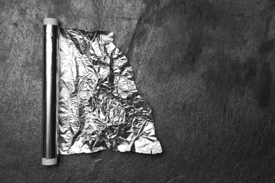 Photo of Roll of aluminum foil on grey table, top view. Space for text