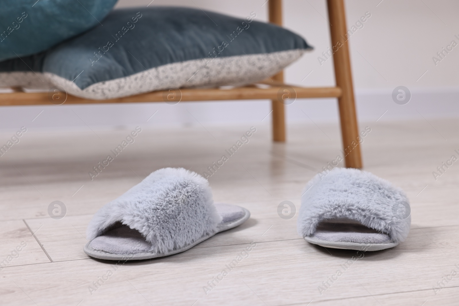 Photo of Grey soft slippers on light wooden floor indoors, closeup