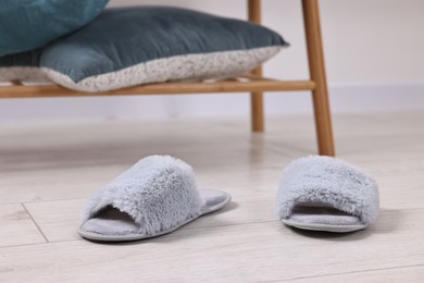 Photo of Grey soft slippers on light wooden floor indoors, closeup