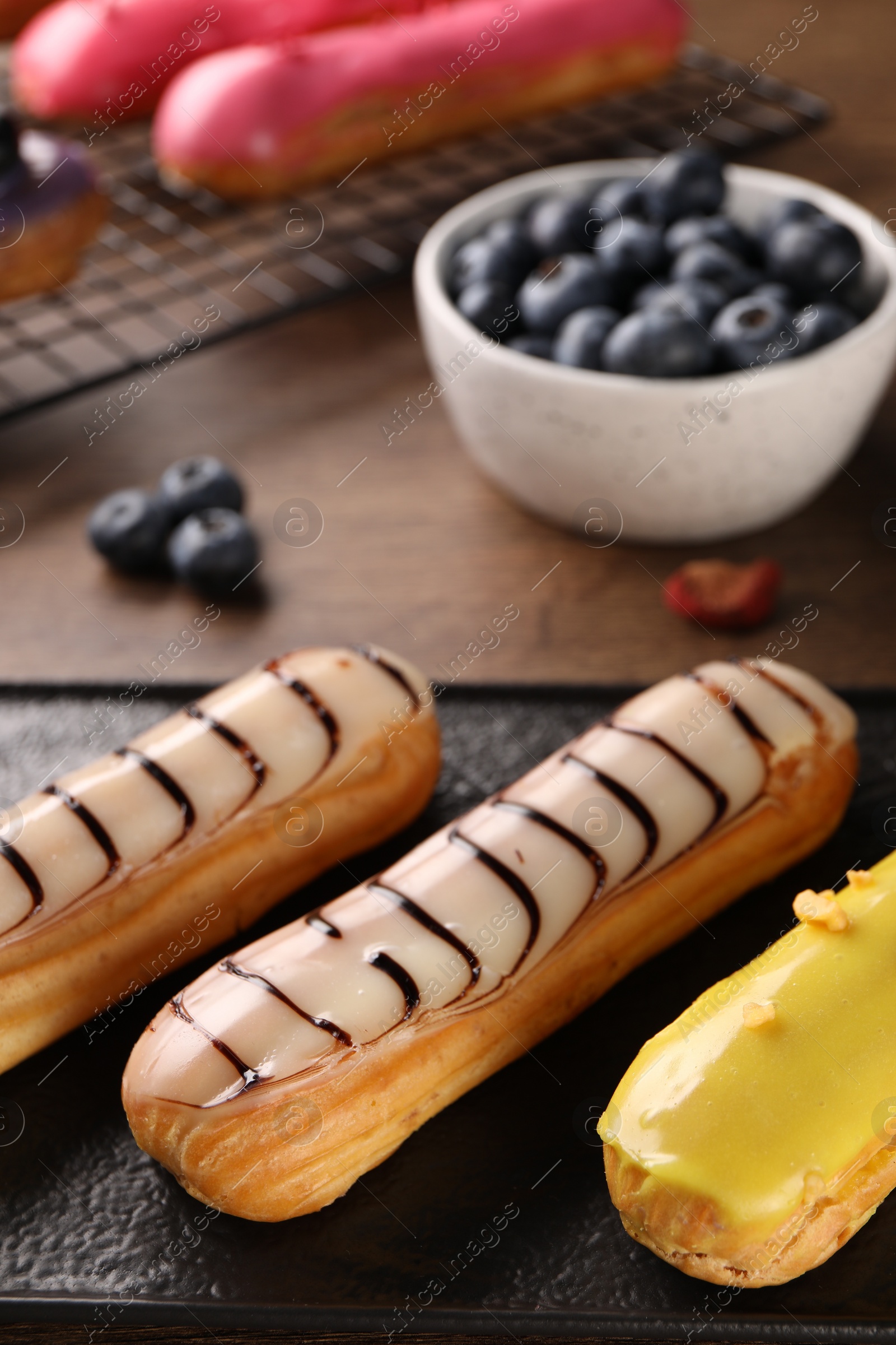 Photo of Different tasty glazed eclairs on table, closeup