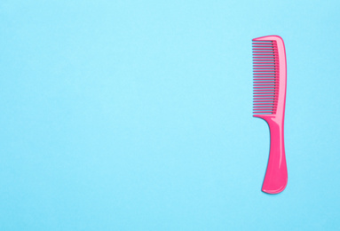 Modern pink hair comb on light blue background, top view. Space for text