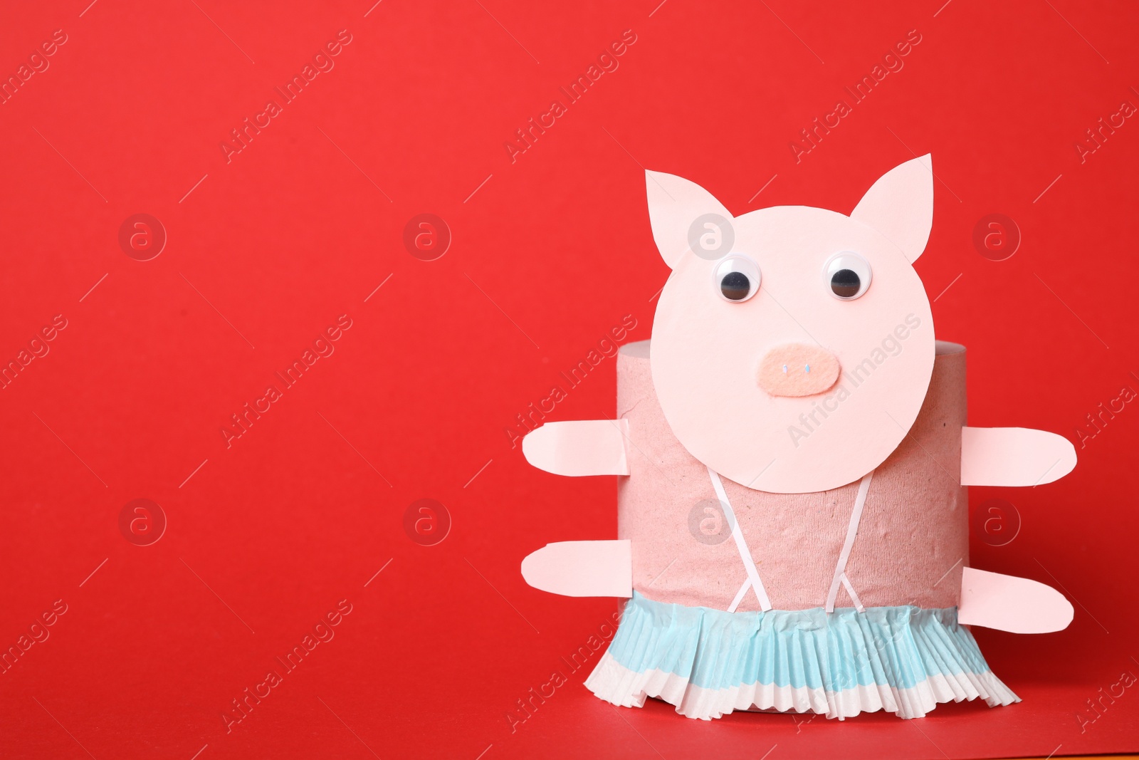 Photo of Toy pig made of toilet paper roll on red background. Space for text