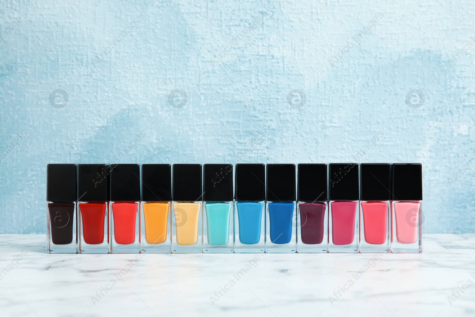 Photo of Bright nail polishes on table against color background. Space for text