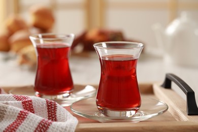 Glasses of traditional Turkish tea on wooden tray indoors