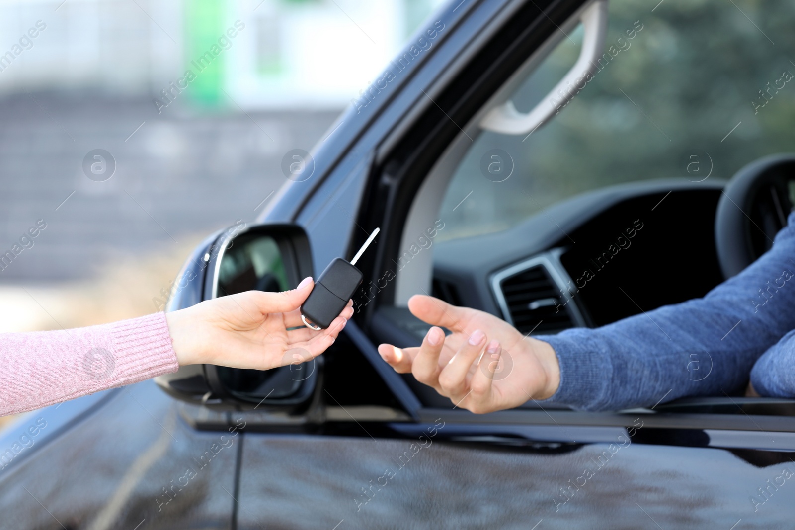 Photo of Agent giving key to man in car outdoors, closeup. Buying new auto