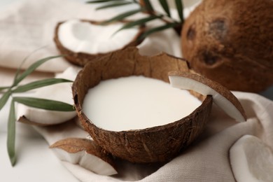 Delicious vegan milk in coconut and pieces of ripe fruit on white table