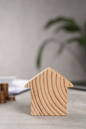 Photo of Wooden house model on grey table, closeup. Financial savings