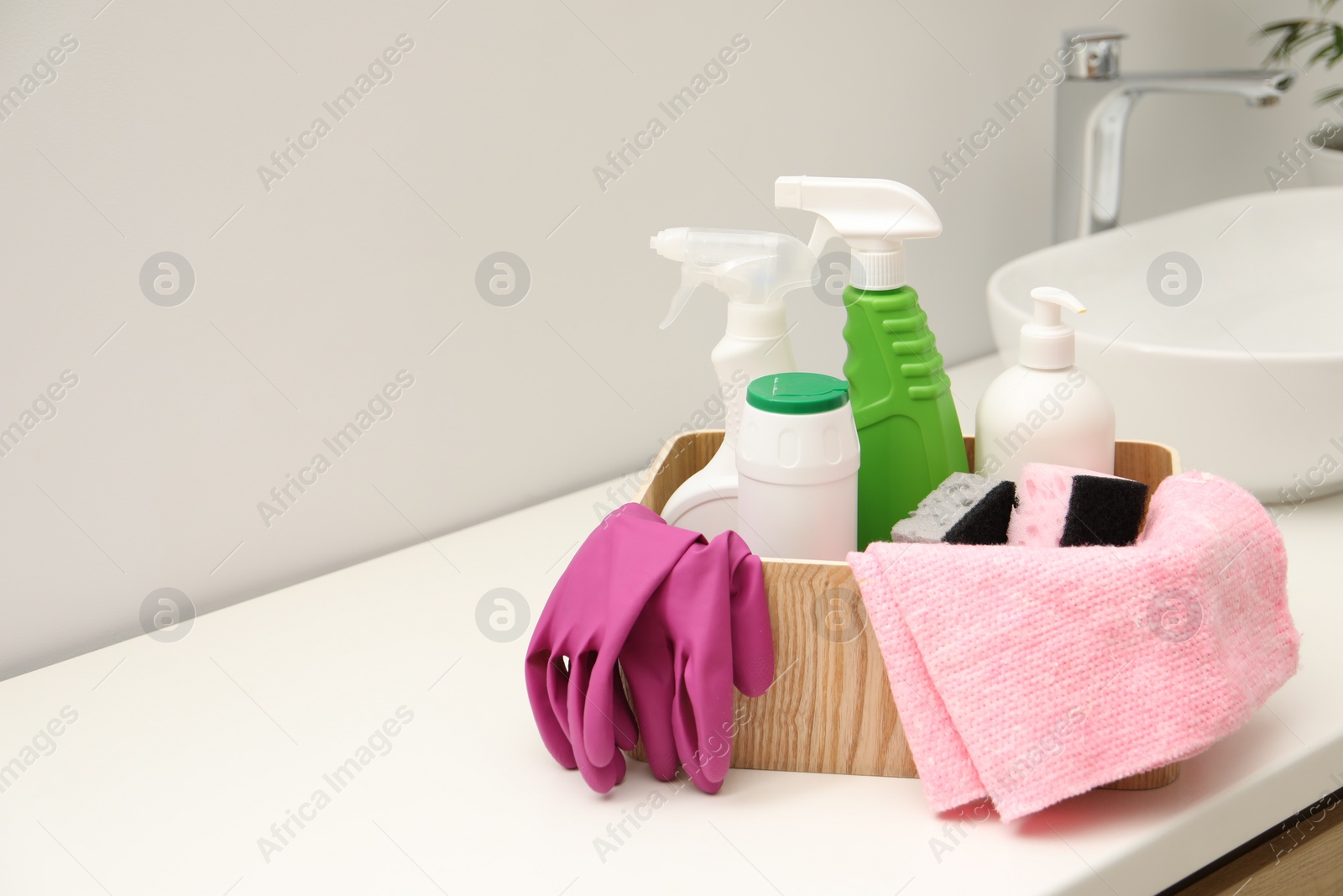 Photo of Different cleaning products in wooden box on countertop indoors, space for text