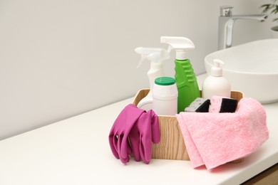 Different cleaning products in wooden box on countertop indoors, space for text