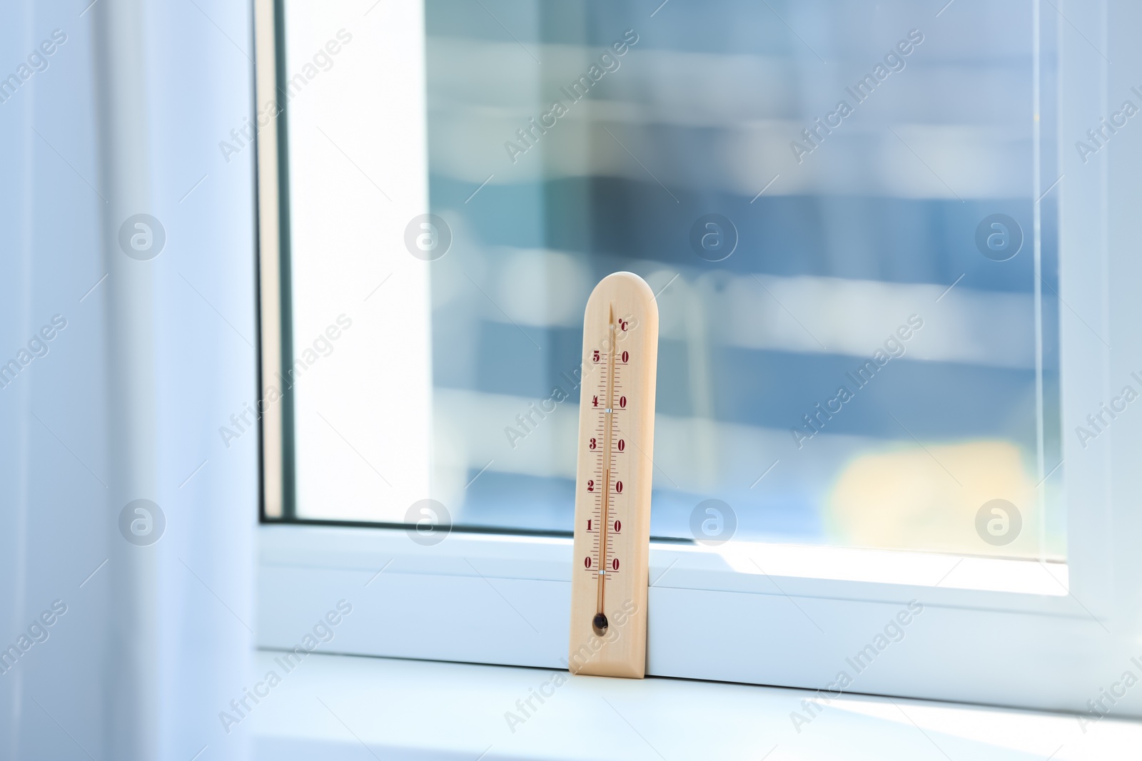 Photo of Wooden weather thermometer on window sill indoors