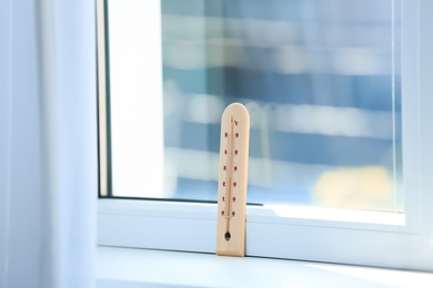 Photo of Wooden weather thermometer on window sill indoors