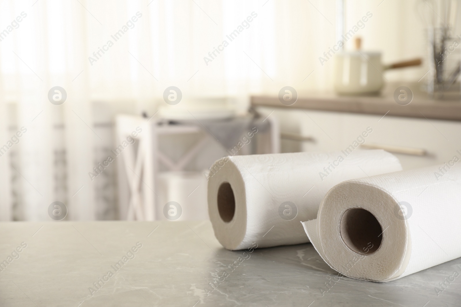 Photo of Rolls of paper towels on white marble table in kitchen, space for text