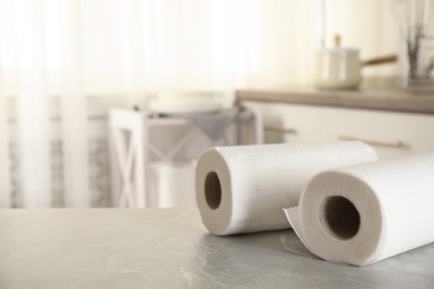 Rolls of paper towels on white marble table in kitchen, space for text