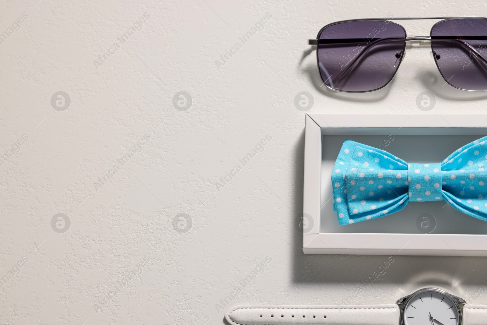 Photo of Stylish light blue bow tie, sunglasses and wristwatch on white background, flat lay. Space for text