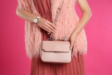 Young woman with stylish bag on pink background, closeup