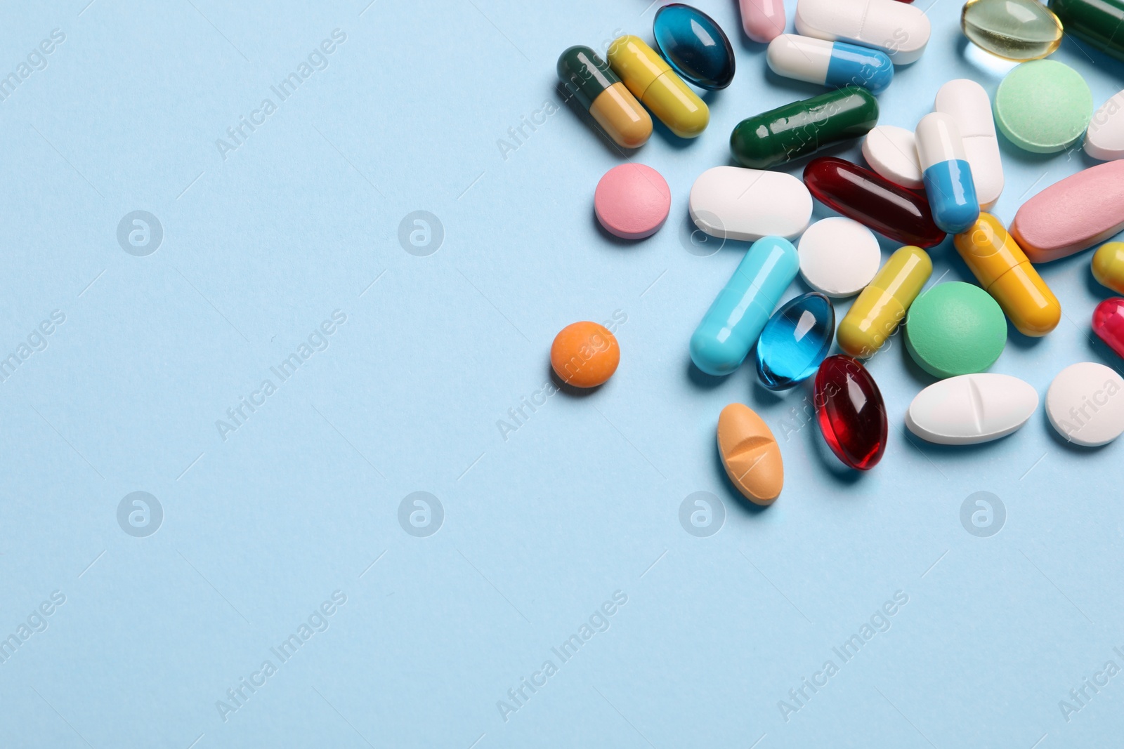 Photo of Many different pills on light blue background, above view