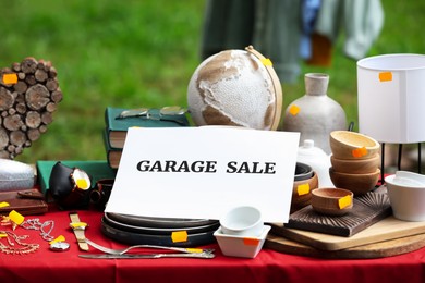 Sign Garage sale and many different items on table outdoors