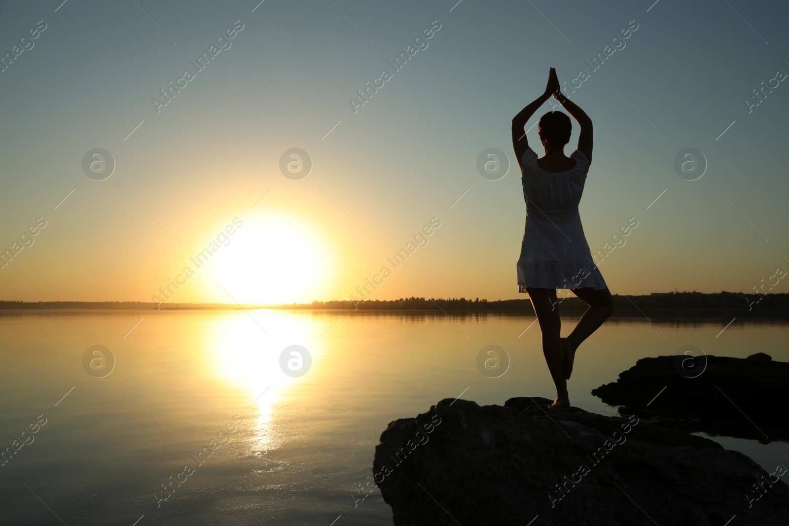 Photo of Woman practicing yoga near river on sunset. Healing concept