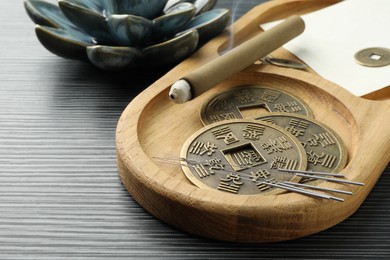 Photo of Acupuncture needles, moxa stick and antique Chinese coins on wooden table, closeup