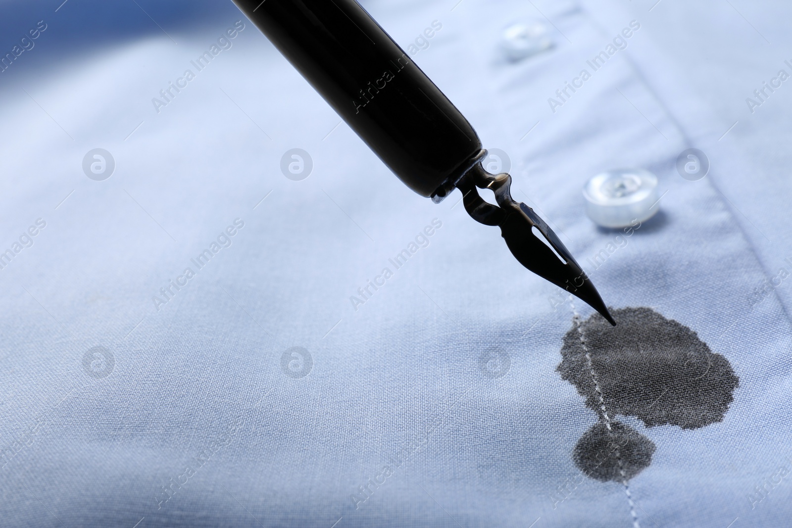 Photo of Black ink stain on light blue shirt and pen, space for text