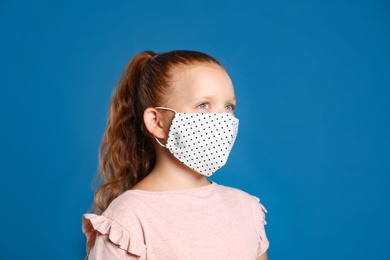 Preteen girl in protective face mask on blue background