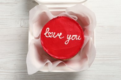 Bento cake with Love You text in takeaway box on white wooden table, top view. St. Valentine's day surprise