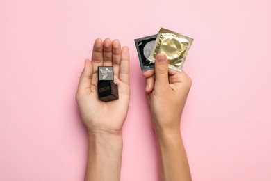 Woman with sex dice and condoms on pink background, top view