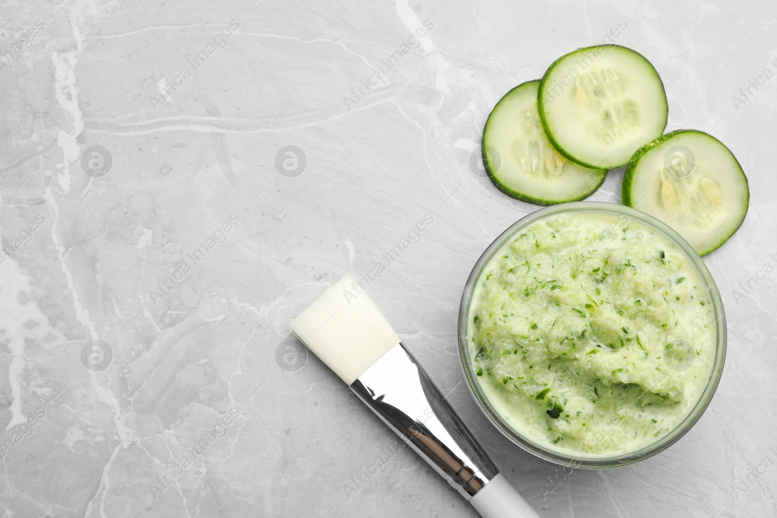 Photo of Handmade face mask and cucumber slices on light marble table, flat lay. Space for text