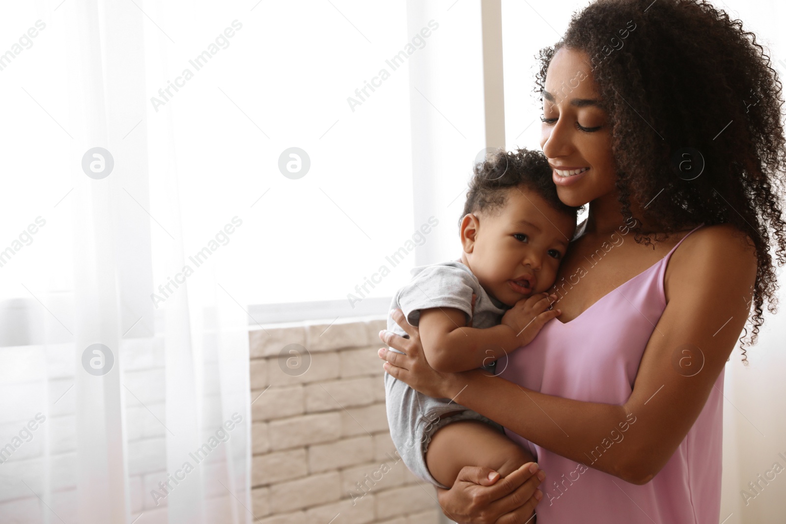 Photo of African-American woman with her baby at home. Happiness of motherhood