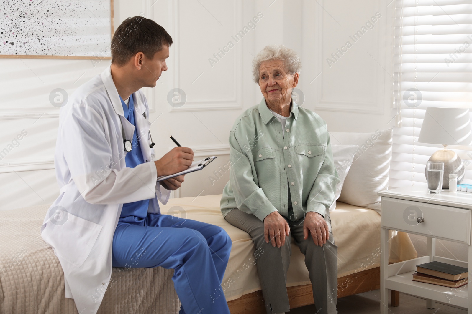 Photo of Caregiver examining senior woman in room. Home health care service