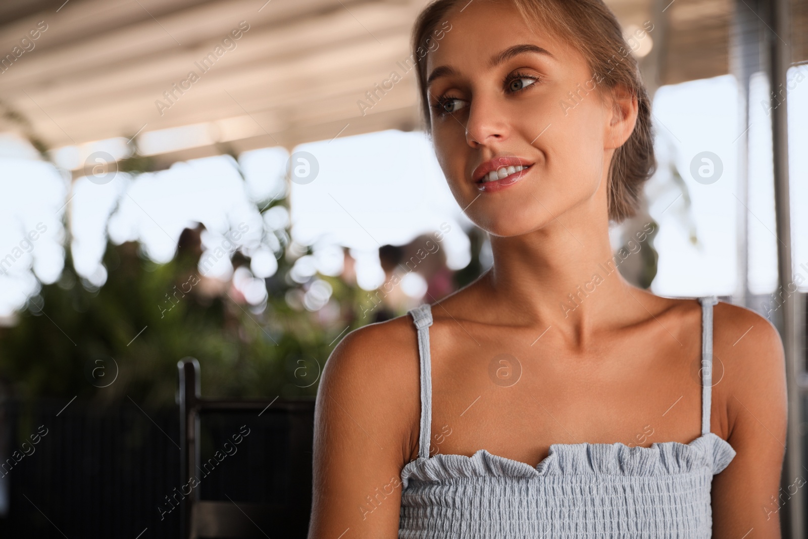 Photo of Beautiful young woman sitting on indoor terrace in cafe, space for text