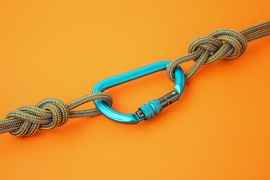 Photo of One metal carabiner with ropes on orange background