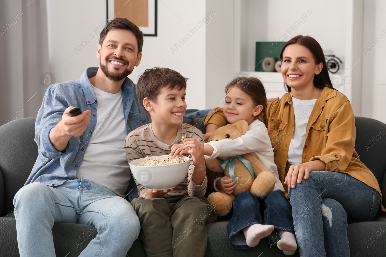 Photo of Family spending time together at home. Father changing TV channels with remote control