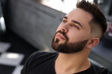 Photo of Handsome young man with fresh haircut and groomed beard in barbershop