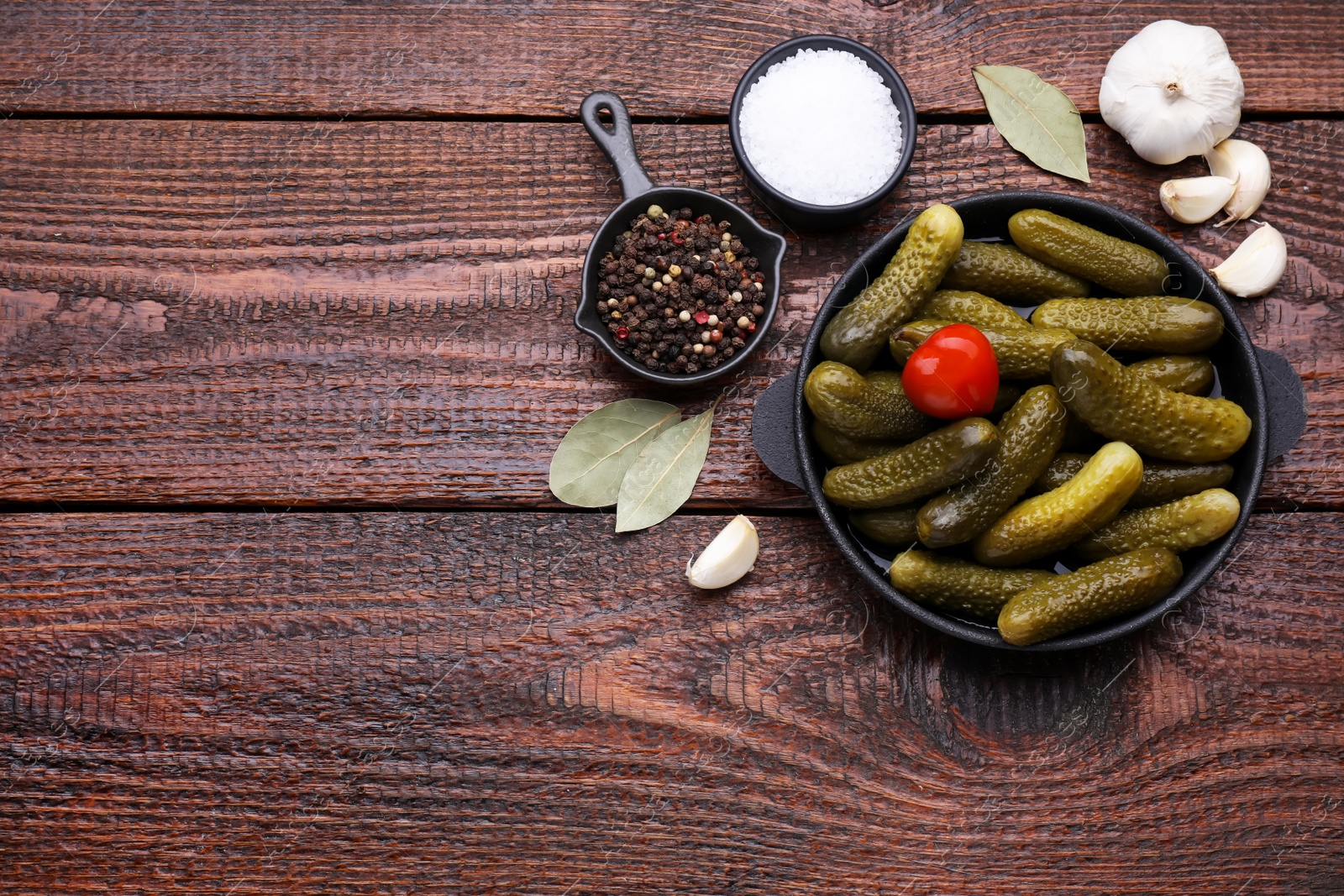 Photo of Pickled cucumbers and ingredients on wooden table, flat lay. Space for text