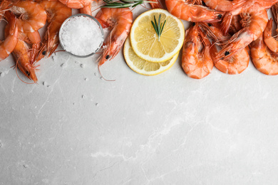 Delicious cooked shrimps with rosemary, salt and lemon on grey marble table, flat lay. Space for text