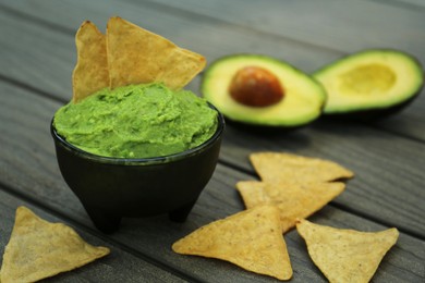 Photo of Delicious guacamole, avocado and nachos on wooden table, closeup. Space for text