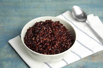 Photo of Bowl with delicious cooked brown rice on color wooden table